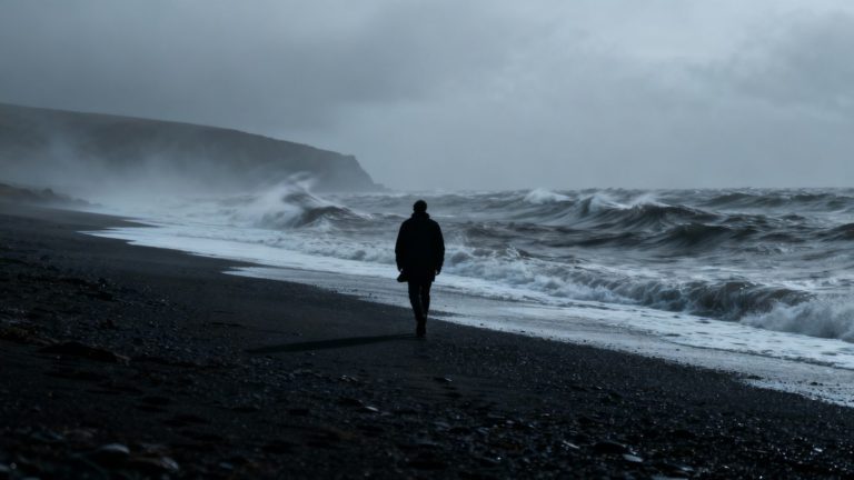 Woman walking alone on a desolate beach.